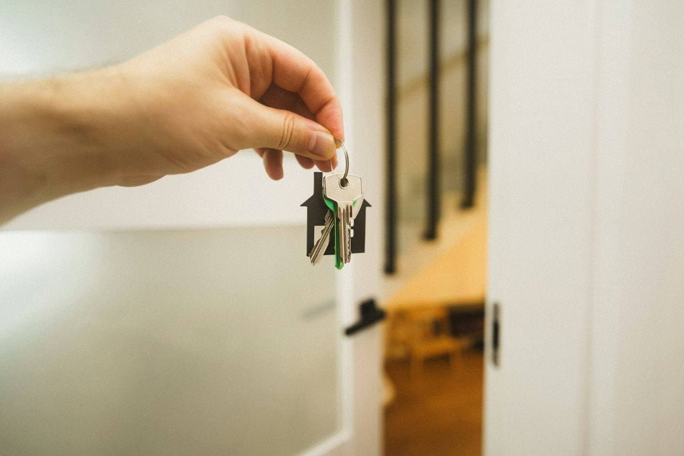 Uma mão estende uma chave diante de uma porta